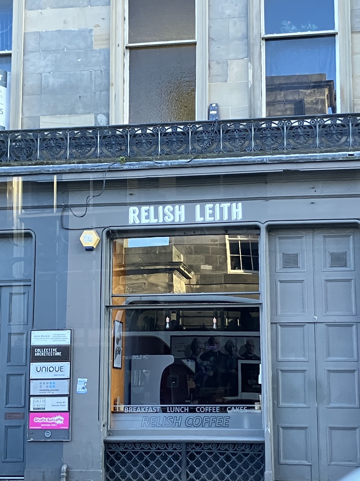 The slate-grey shopfront: RELISH LEITH in shadowed white letters on the fascia, and Breakfast, Lunch, Coffee, Cakes and Relish Coffee along the bottom of the window, under a wrought-iron balcony.